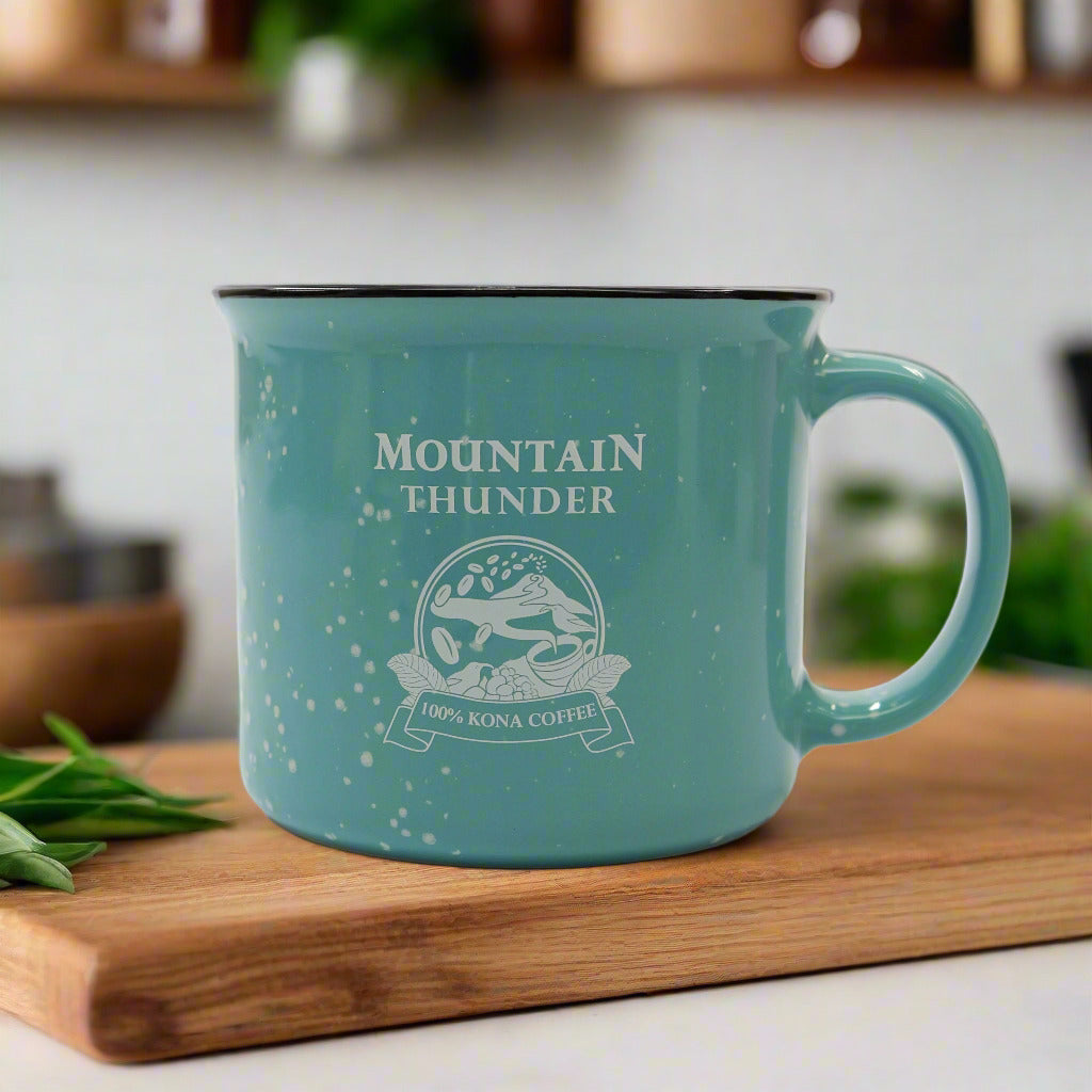 teal ceramic campfire style mug with black and white speckles, white interior, black rim and pink mountain thunder logo