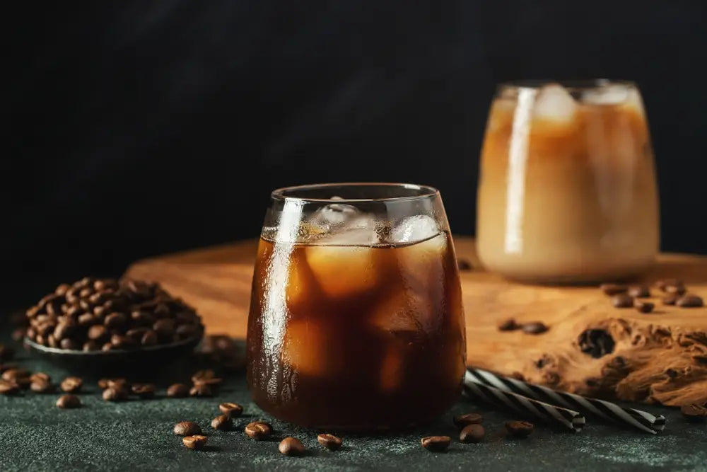 A glass of iced coffee near some coffee beans