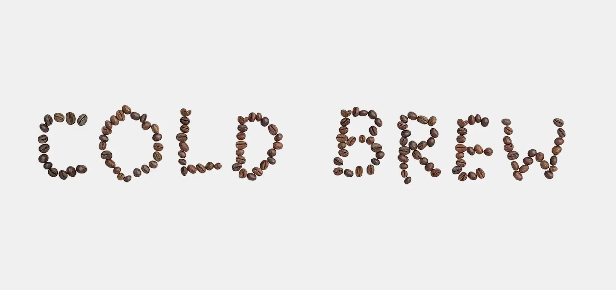 Coffee beans spelling out 'COLD BREW' on a light background