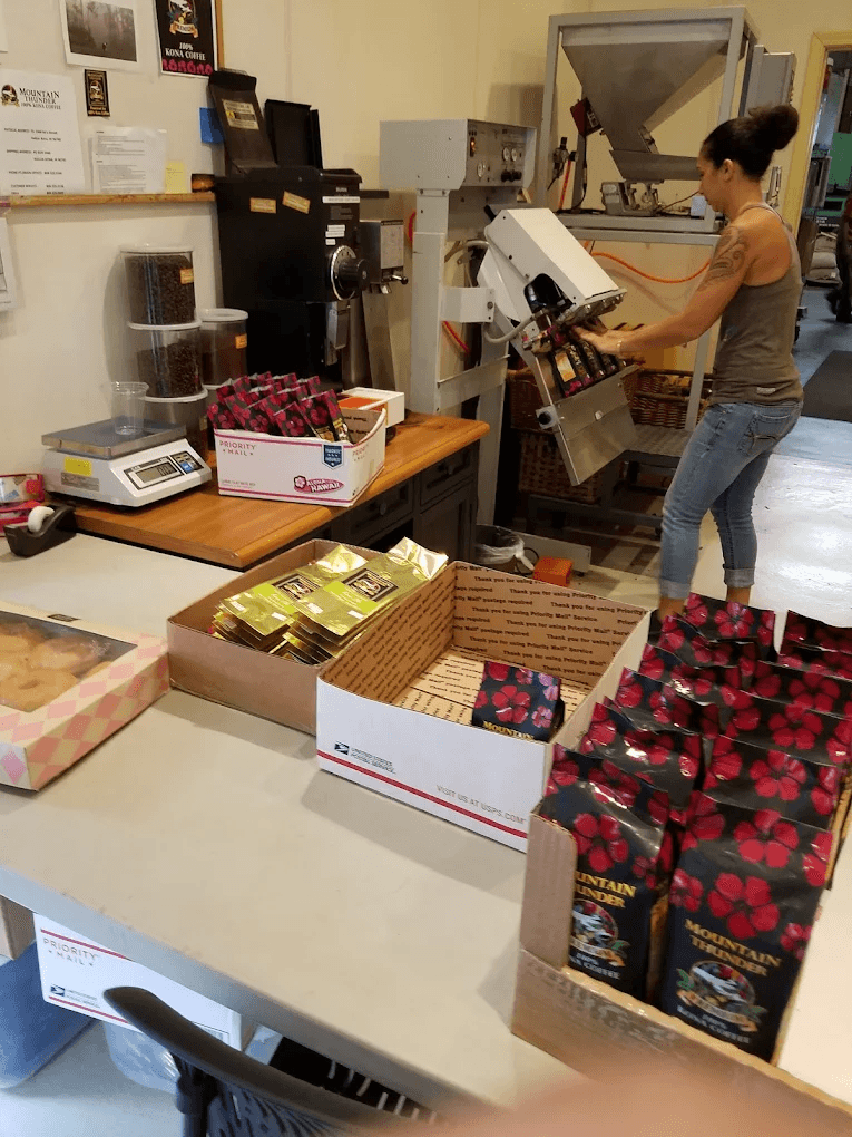 Person packaging coffee boxes in a warehouse setting