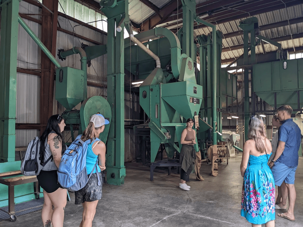 Group of people visiting a large green industrial machine inside a building.